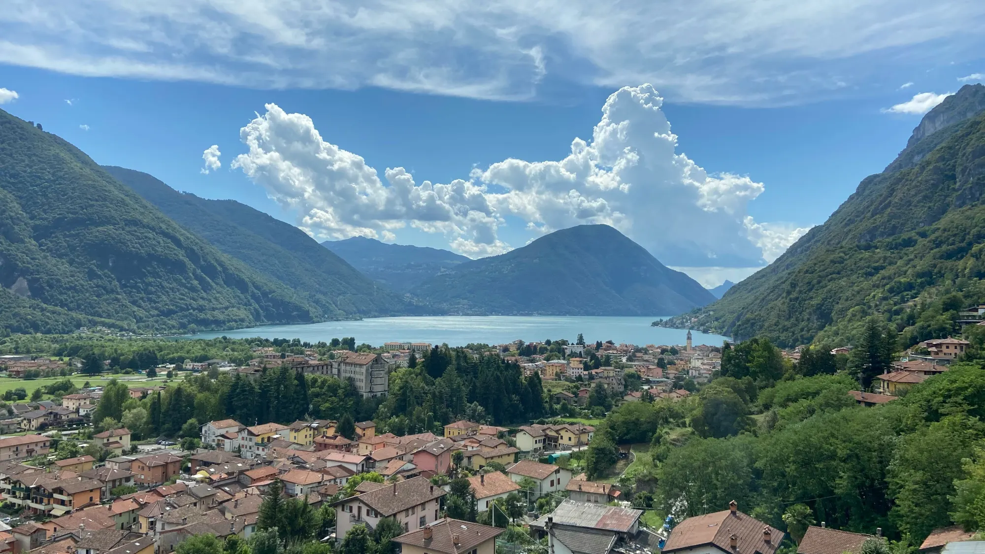 Il lago di Lugano tra le montagne, con i tetti del paese in primo piano